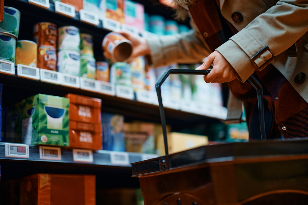 Smart retail technology in action: A shopper picks up a canned product in a supermarket with IoT-enabled electronic shelf labels. Digital pricing and real-time inventory tracking enhance retail efficiency and customer experience with dynamic pricing and stock updates.